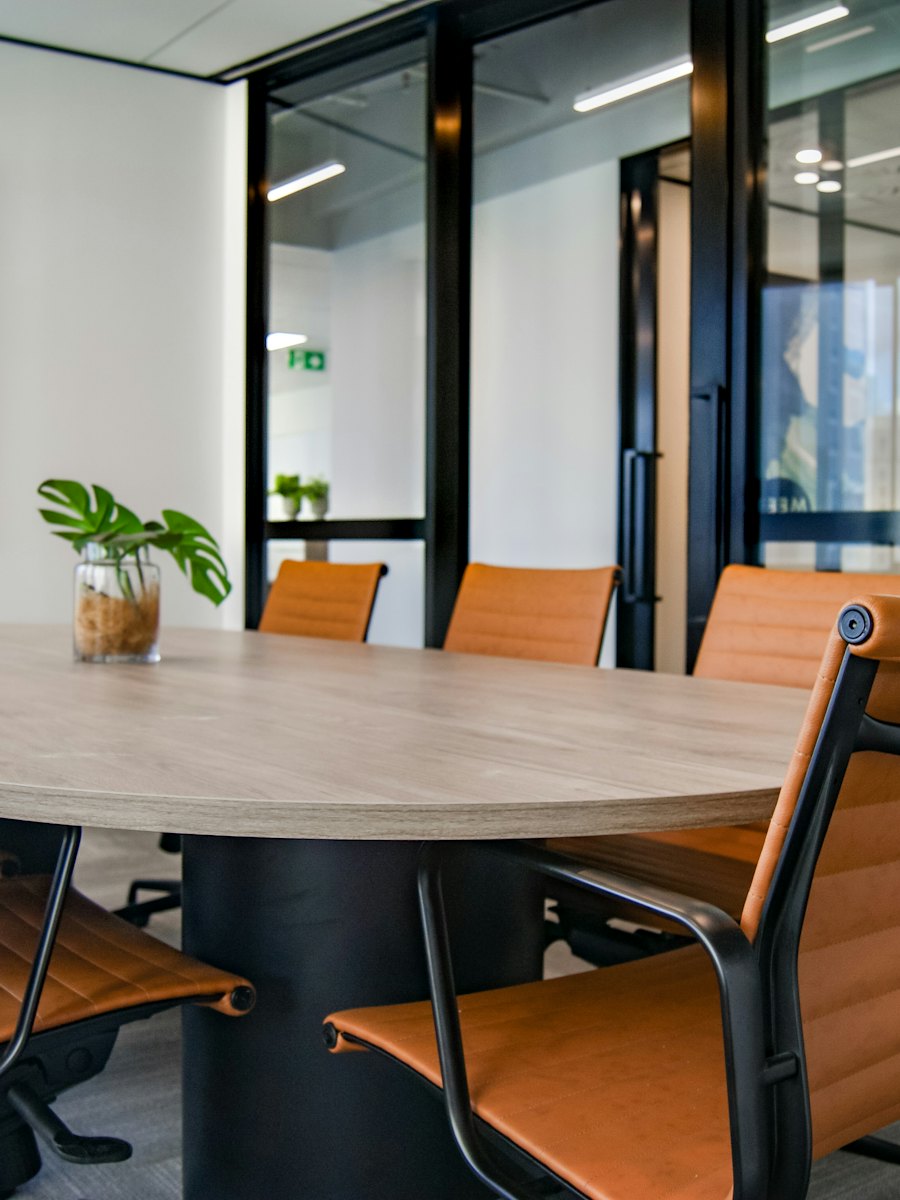 A conference room with a round wooden table and leather chairs