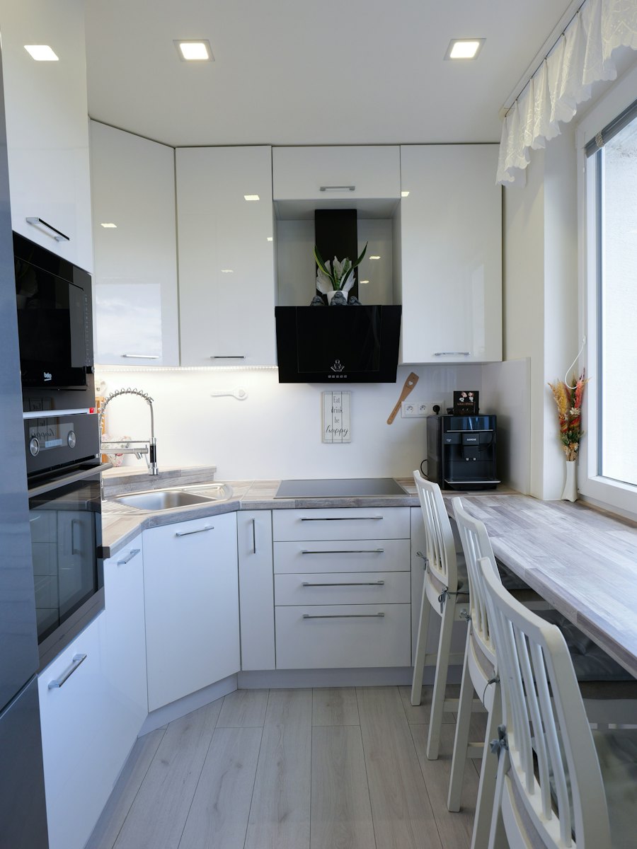 A white kitchen with clear counters, built-in ovens and island seating